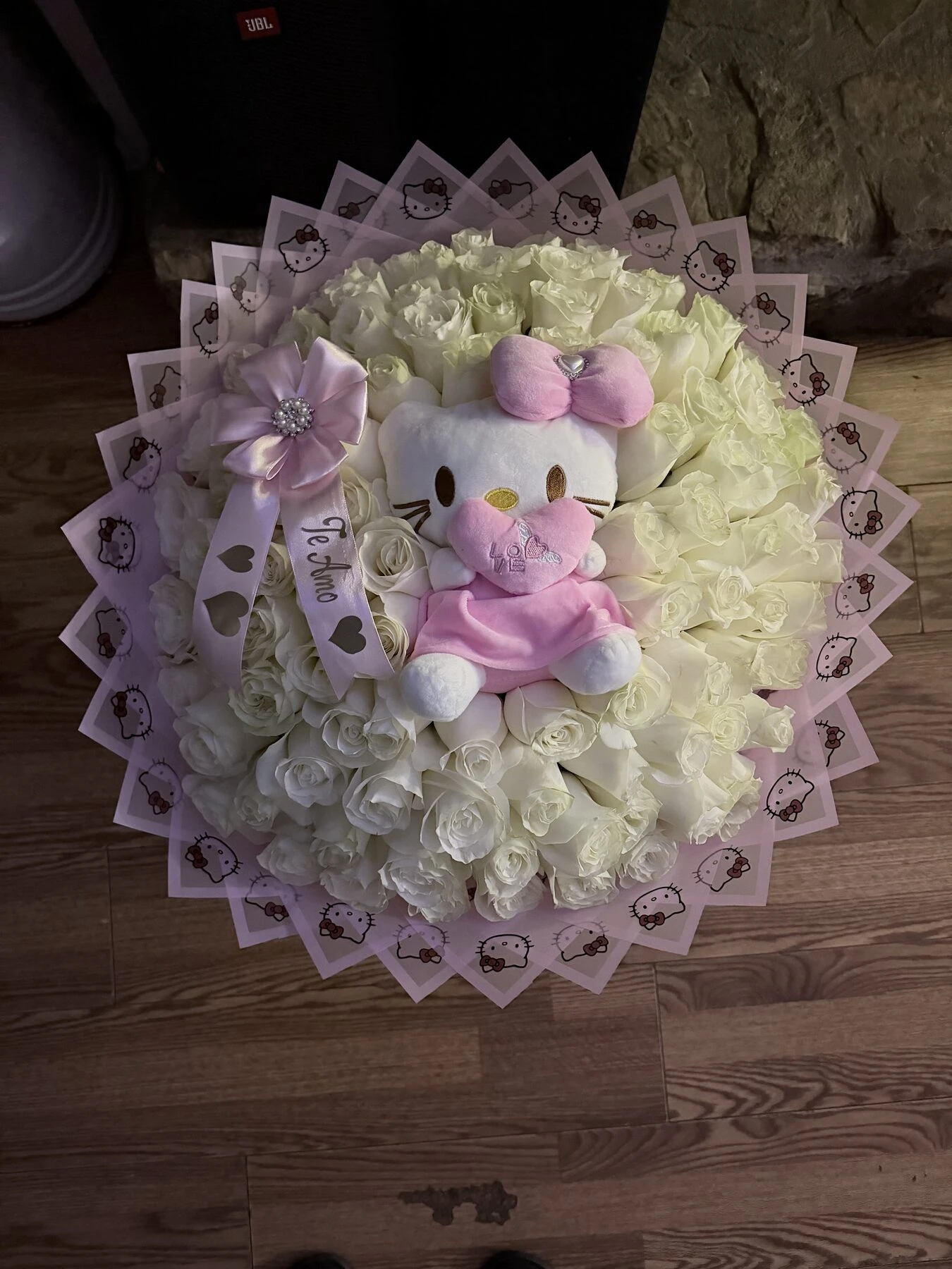 Arreglo floral claro con un pequeño peluche rosa en el centro.