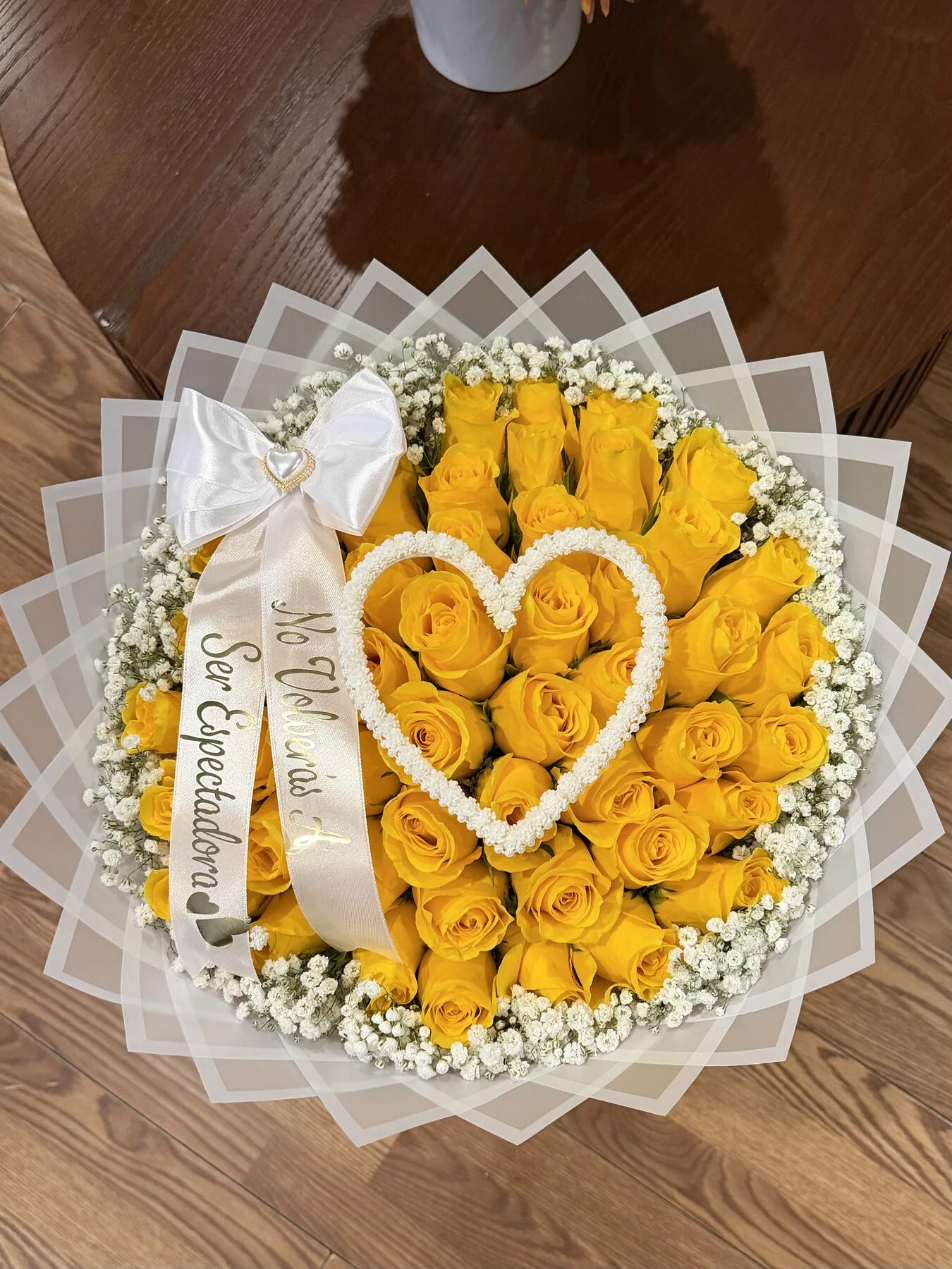Flores amarillas con forma de rosa y un pequeño corazón blanco en una envoltura clara en capas.