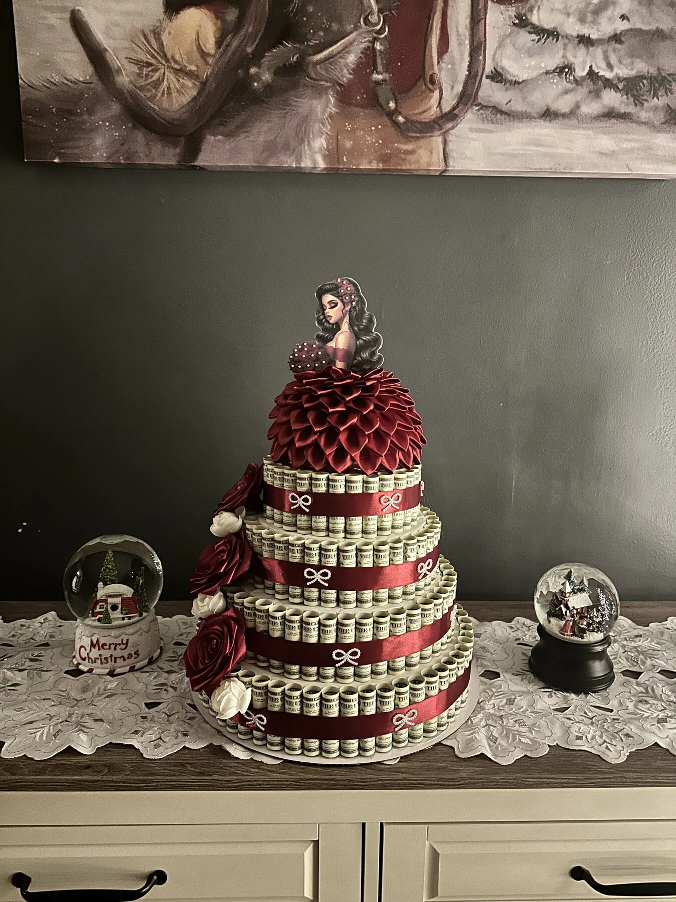 Arreglo rojo en niveles con una pequeña figura encima y detalles decorativos alrededor.