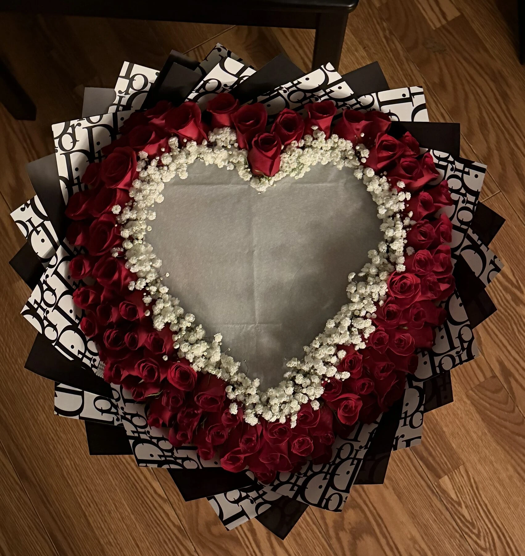 Flores rojas delinean un gran centro en forma de corazón, bordeado con flores blancas pequeñas.