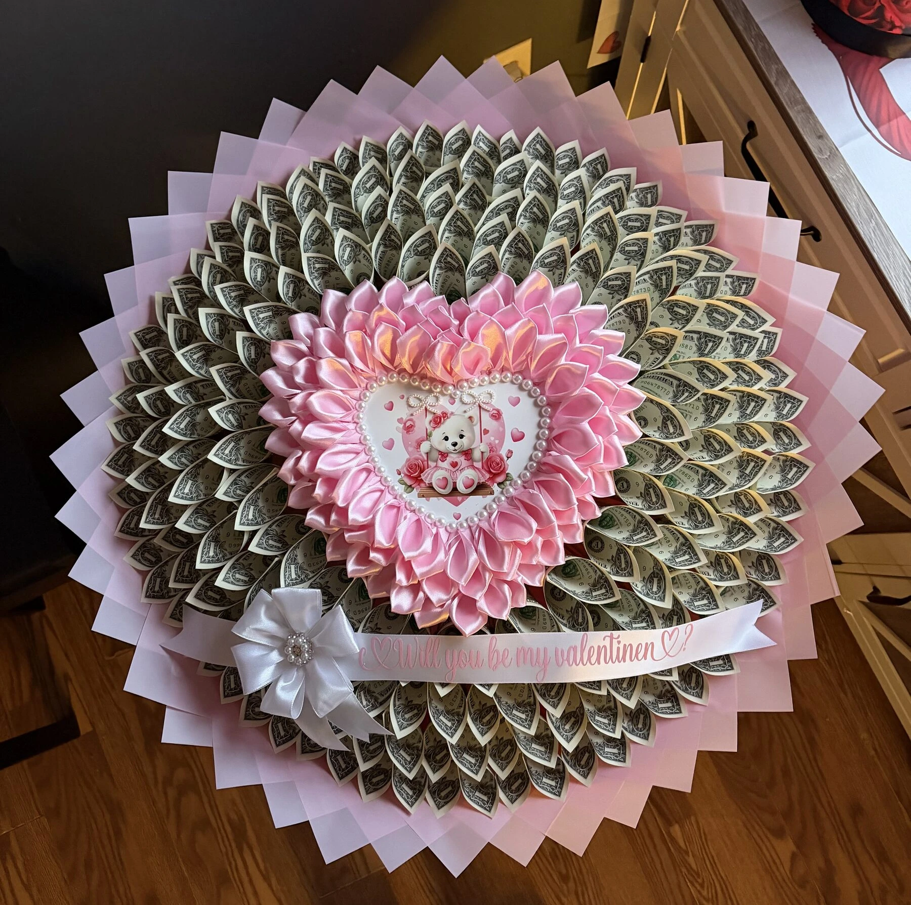 Arreglo rosa en forma de corazón con envoltura clara en capas y un pequeño detalle central.