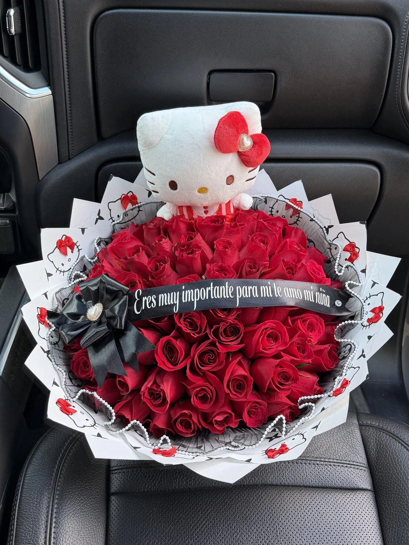 Arreglo floral rojo con un personaje blanco de peluche, un lazo oscuro y envoltura estampada.