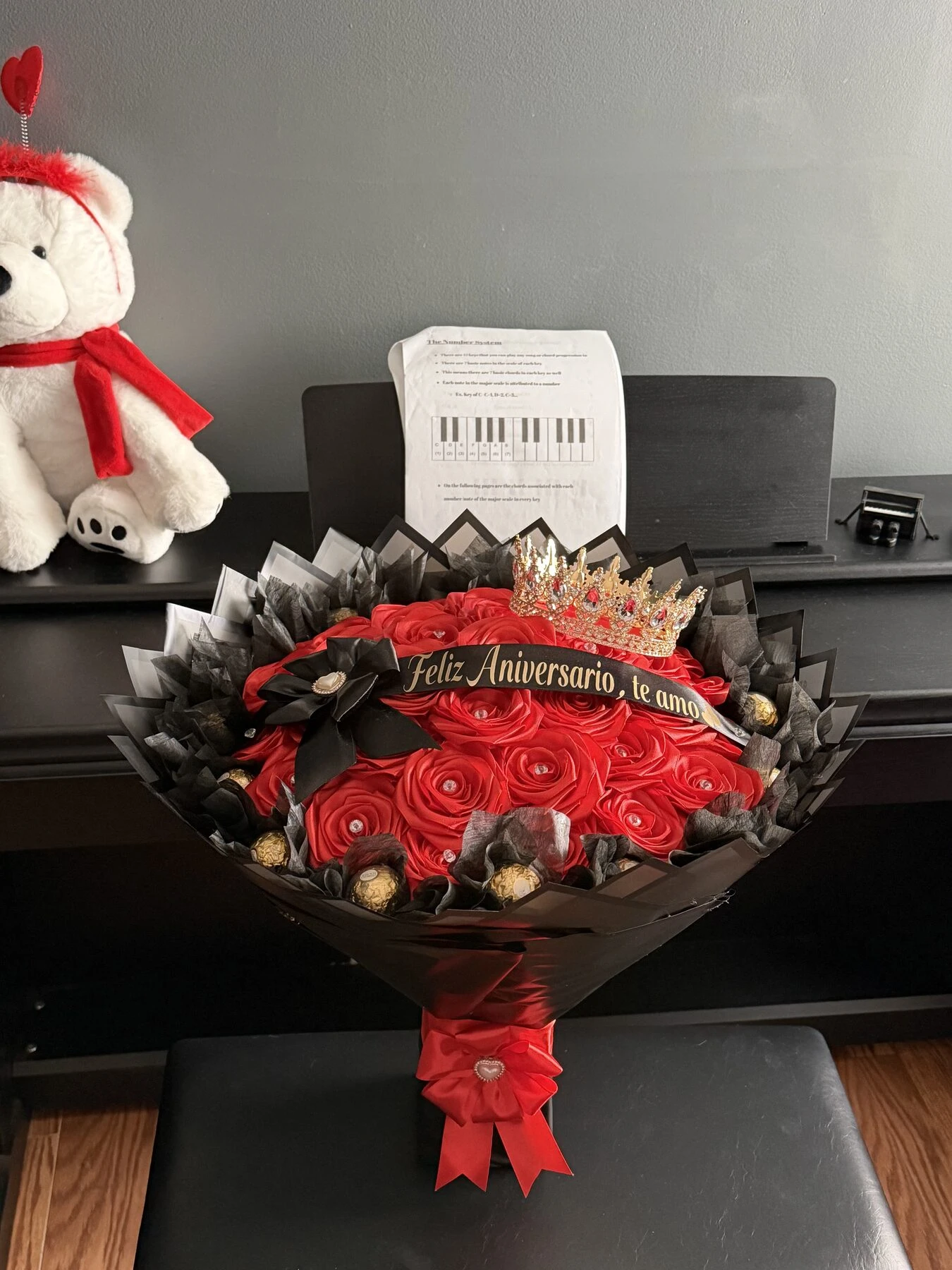 Pequeño arreglo rojo en un florero con una cinta y una banda con mensaje.