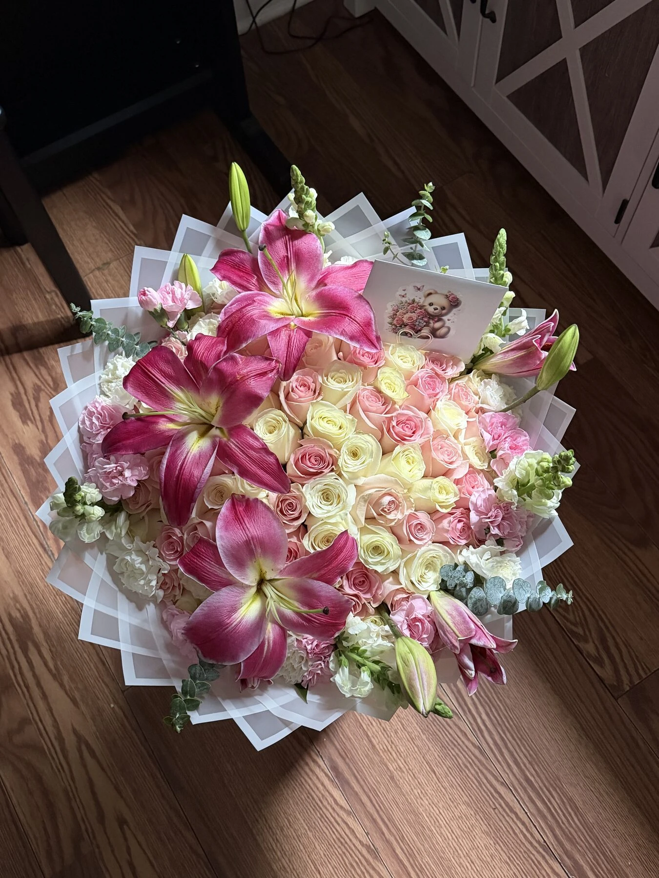 Flores grandes rosas y flores pequeñas blancas y rosa pálido con follaje en una envoltura clara.